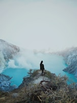a person sitting on a cliff overlooking a body of water