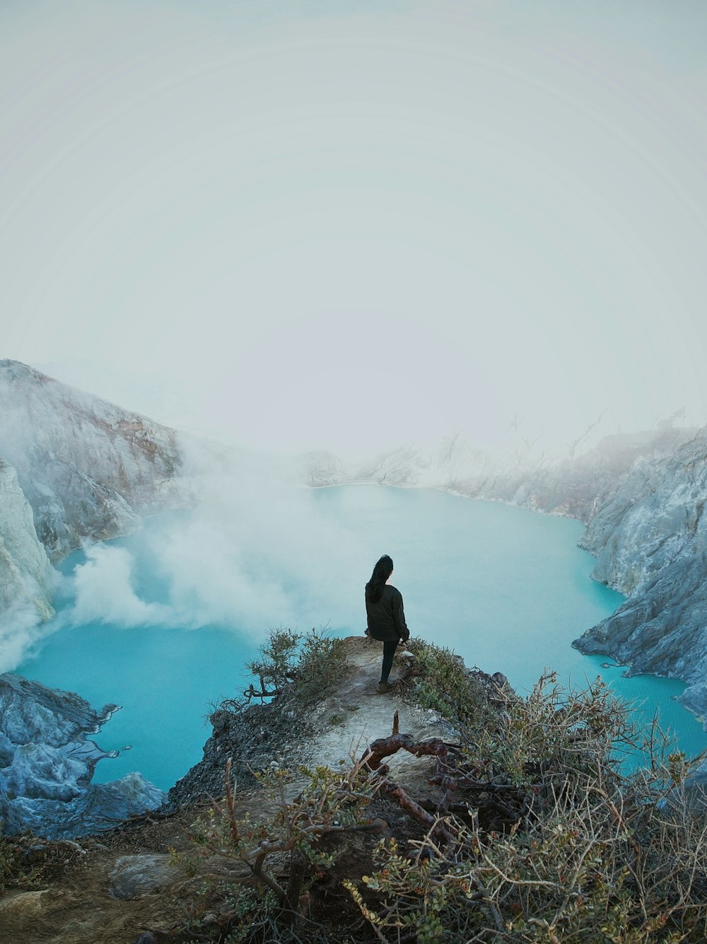 a person sitting on a cliff overlooking a body of water