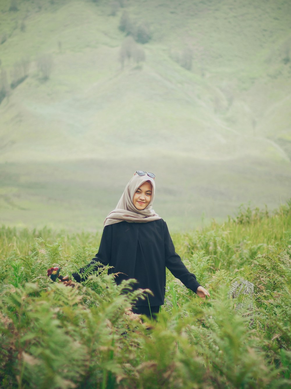 a woman in a hijab walking through tall grass