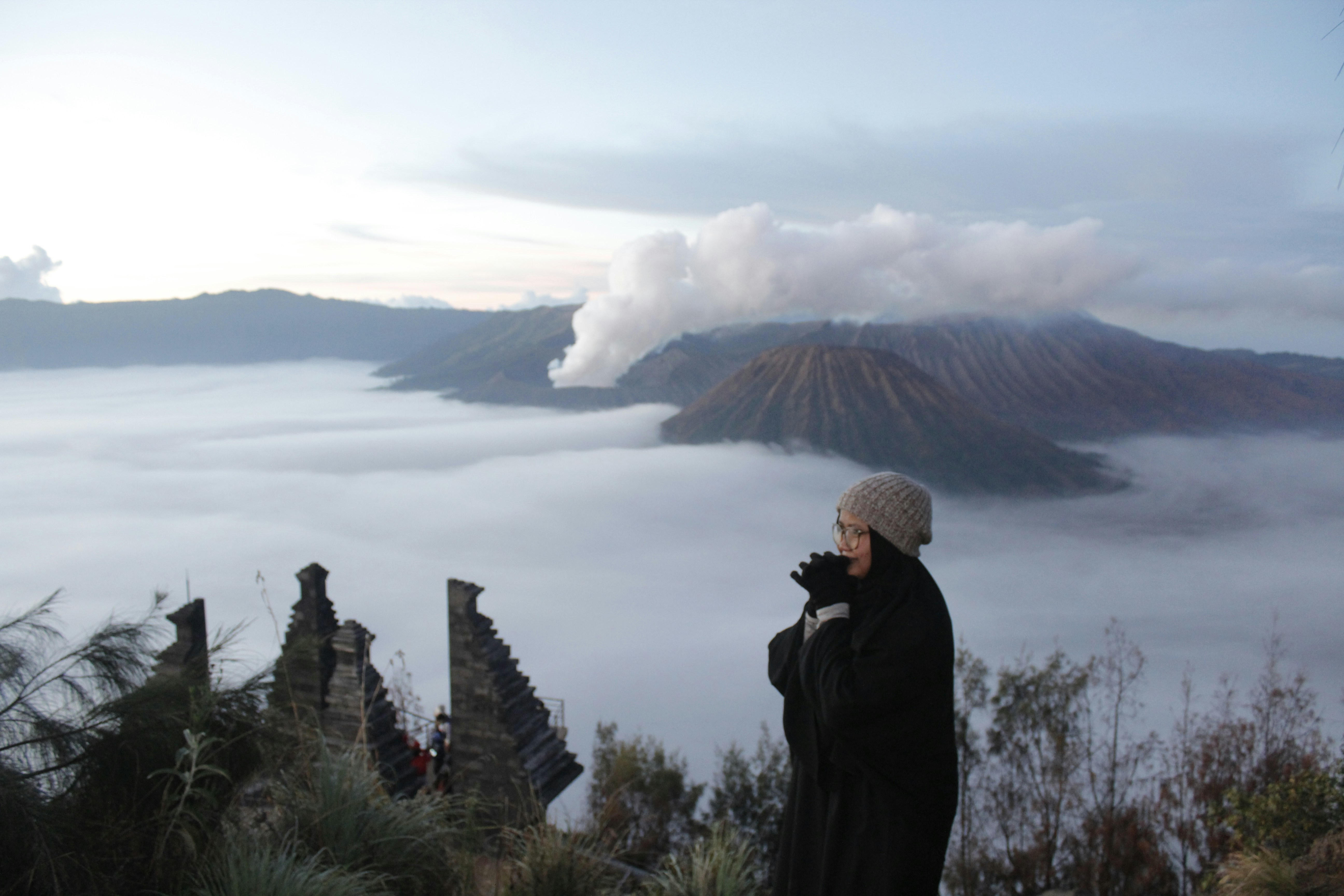 a woman standing on top of a mountain looking at the clouds