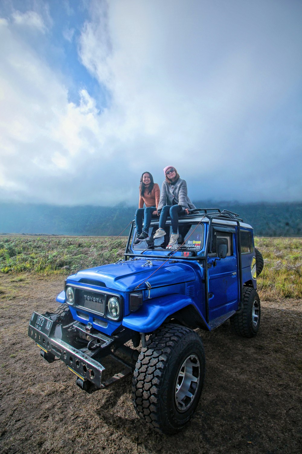 a couple of people sitting on top of a blue truck