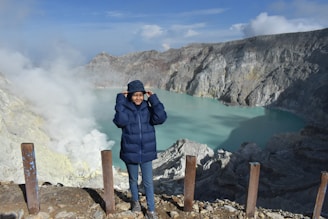 a man in a blue jacket standing on a mountain