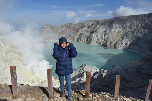 a man in a blue jacket standing on a mountain