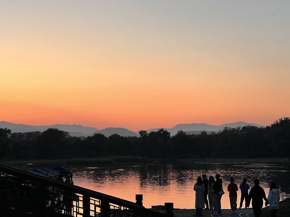 a group of people standing next to a body of water