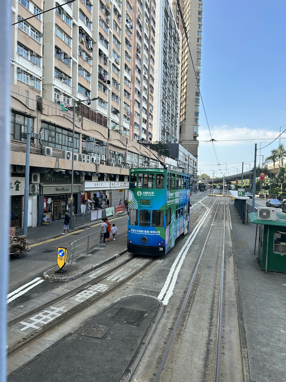 a blue and green double decker bus driving down a street