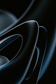 Smooth, glossy, abstract shapes in a dark color palette with overlapping curves and a futuristic appeal.