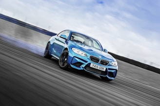 A dynamic shot of the Raske Racing Team's sleek race car speeding on a rally track under a clear blue sky.