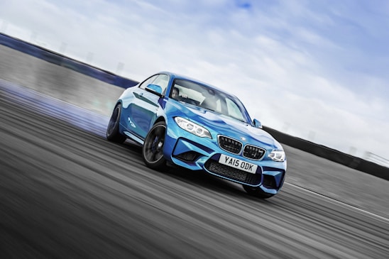 A dynamic shot of the Raske Racing Team's sleek race car speeding on a rally track under a clear blue sky.