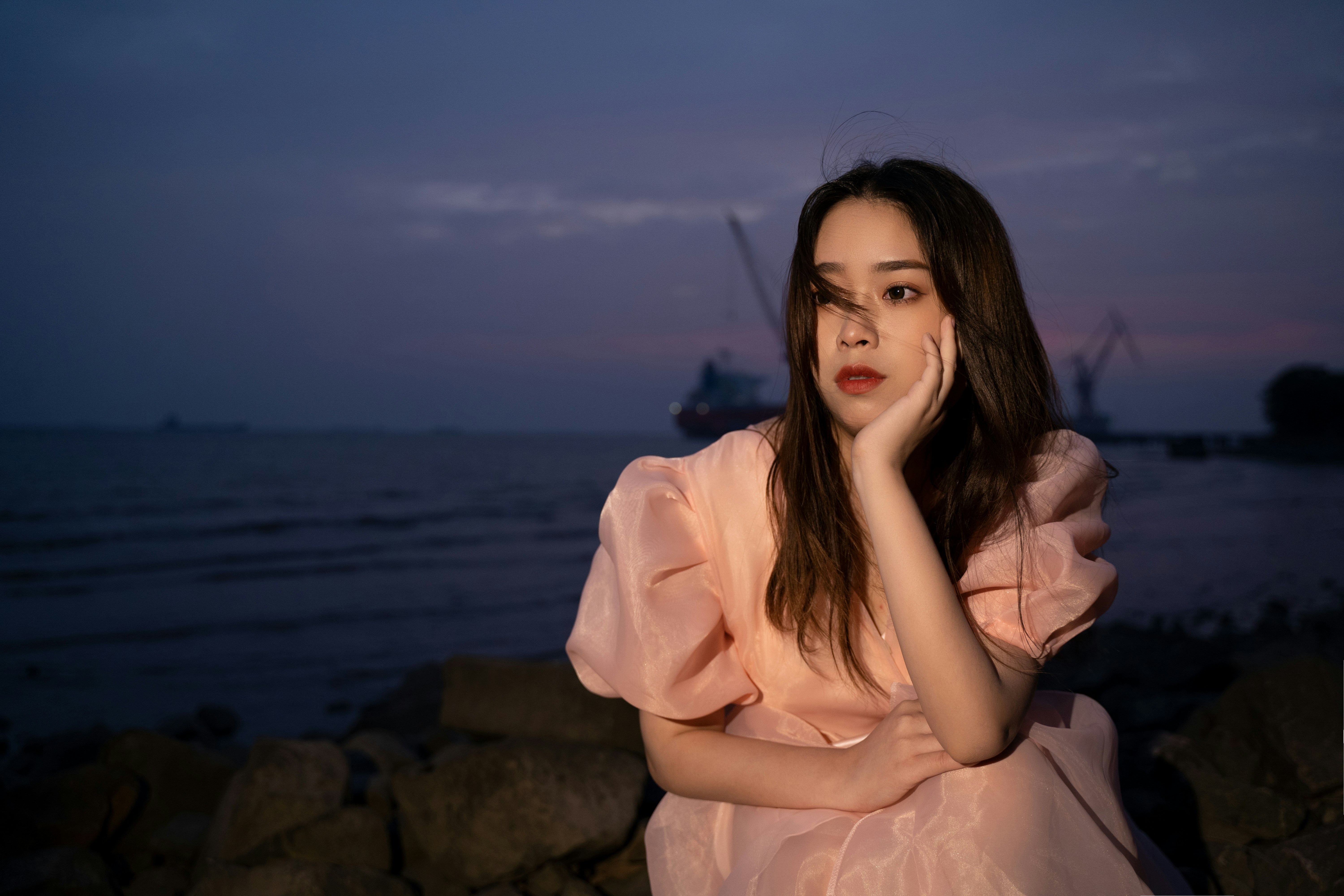 A woman in a pink dress sitting on rocks photo – Free Woman Image on ...