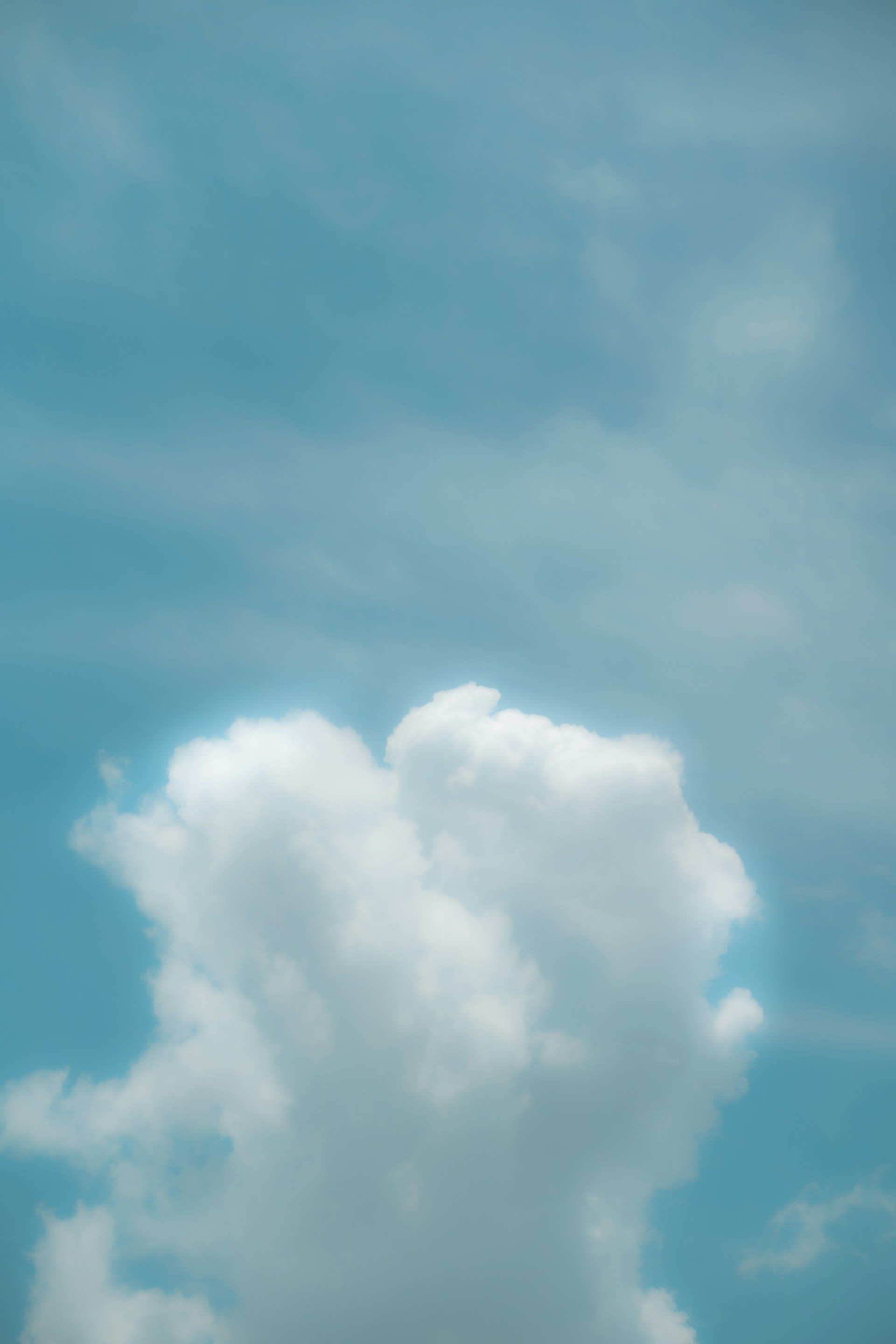 a plane flying in the sky with a cloud in the background
