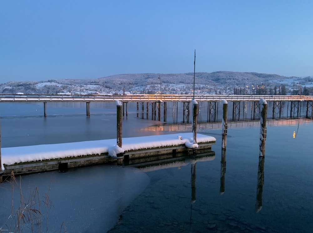 a pier covered in snow next to a body of water