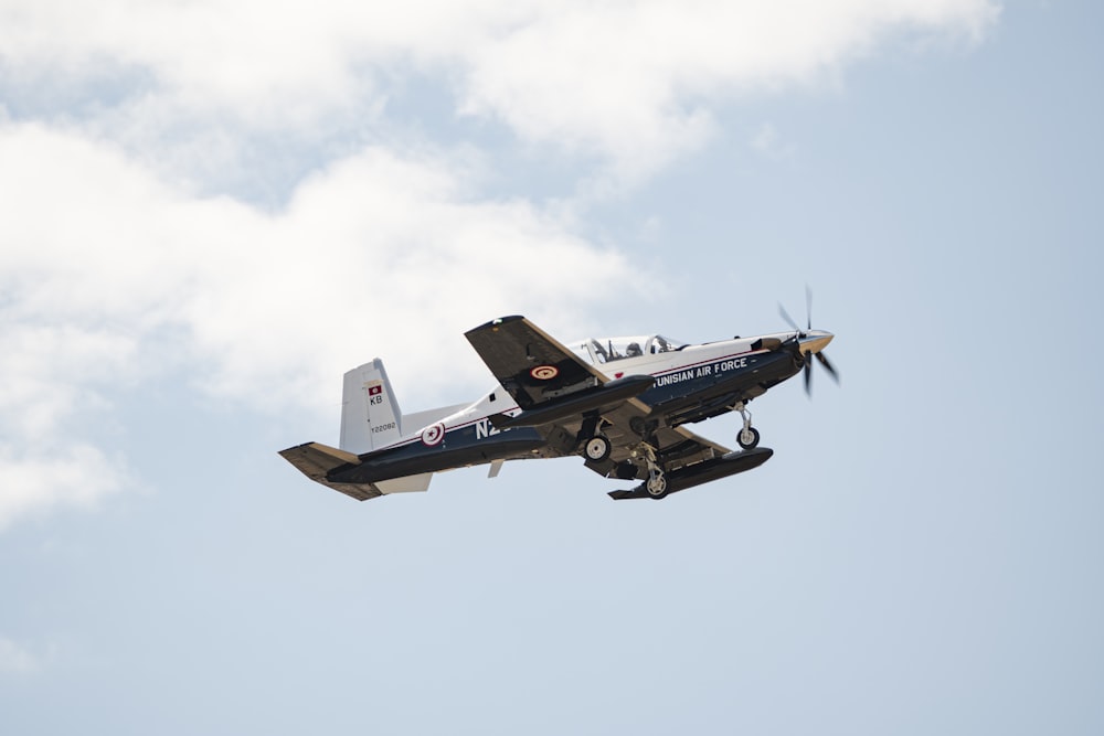 a small propeller plane flying through a cloudy blue sky