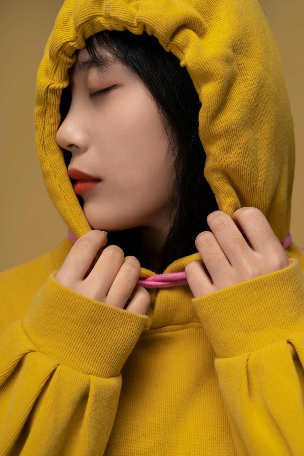 a woman in a yellow hoodie with her eyes closed