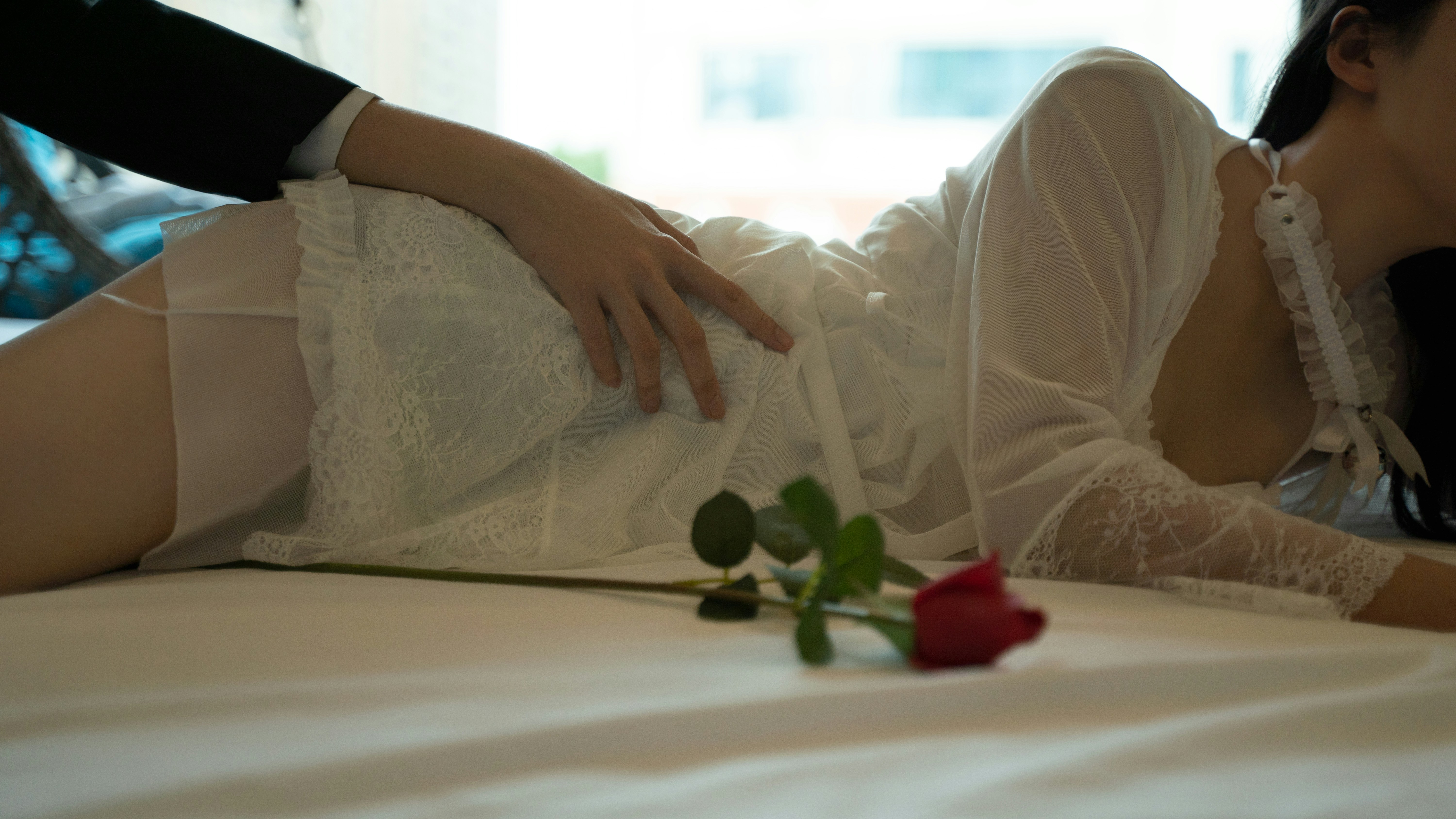 a woman laying on top of a bed next to a rose