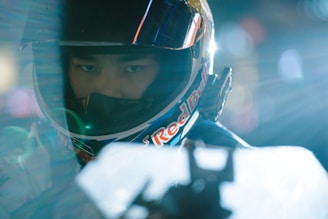 Close-up of a racing helmet with vibrant sponsor logos under bright track lights