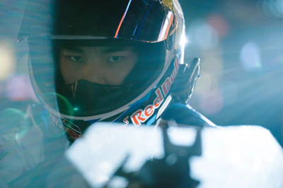Close-up of a high-performance racing helmet with green accents under dramatic lighting.
