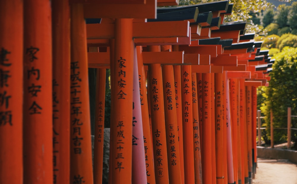 a row of orange and black poles with asian writing on them
