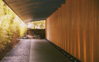 A modern walkway made of large-format pavers leading through a garden with subtle gold accent lighting.