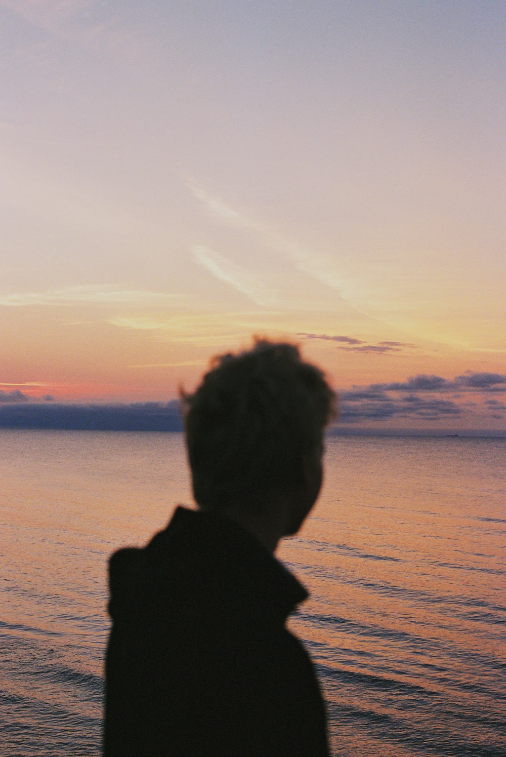 a person standing on a beach watching the sunset