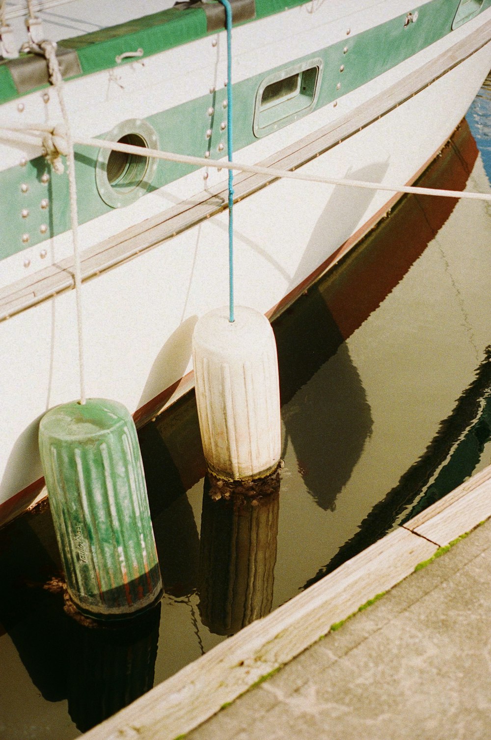 a green and white boat docked at a dock