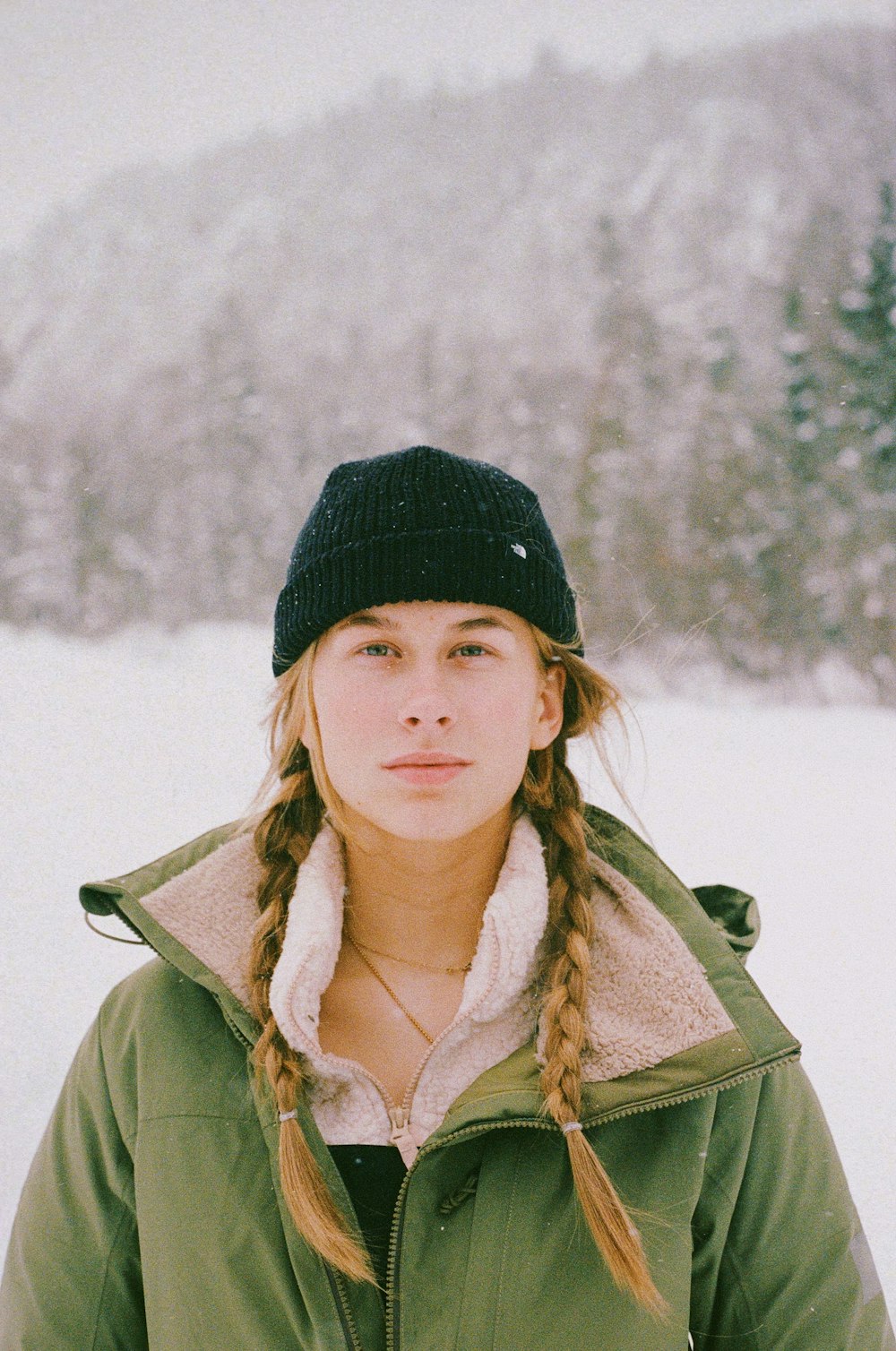 a woman standing in the snow wearing a hat