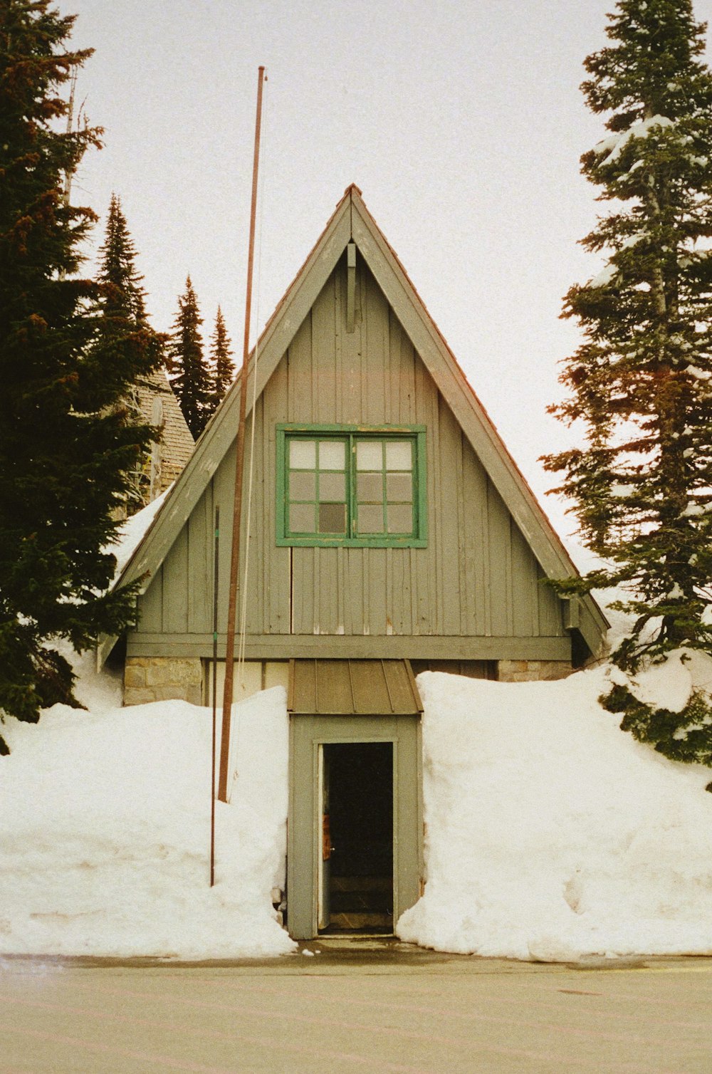a building with a green window and a lot of snow on the ground