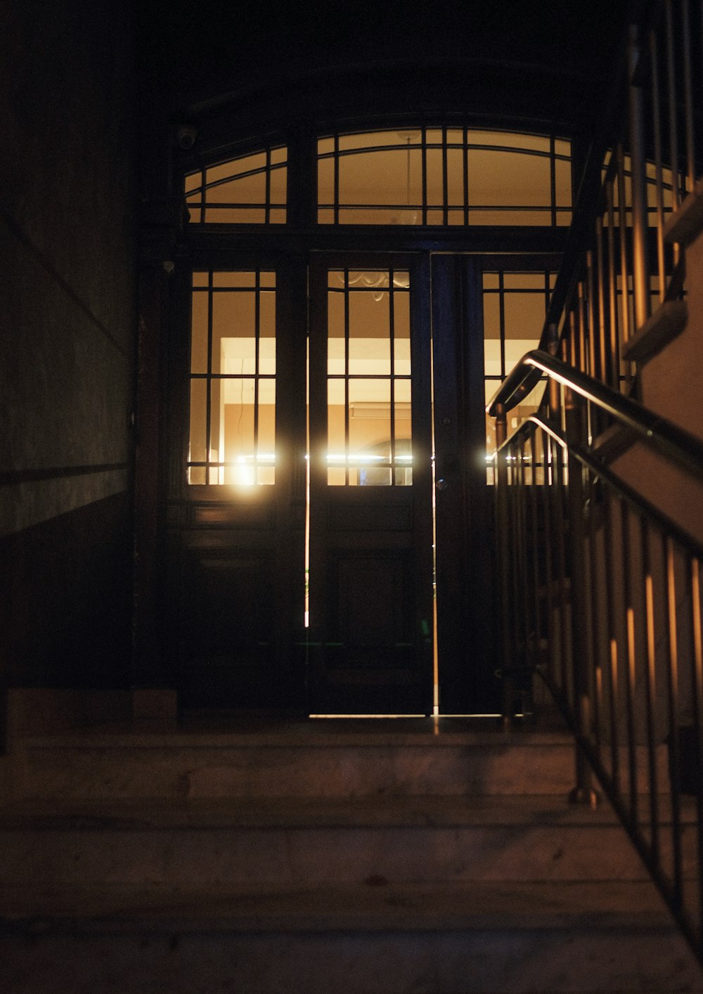 un escalier menant à un bâtiment avec une porte éclairée