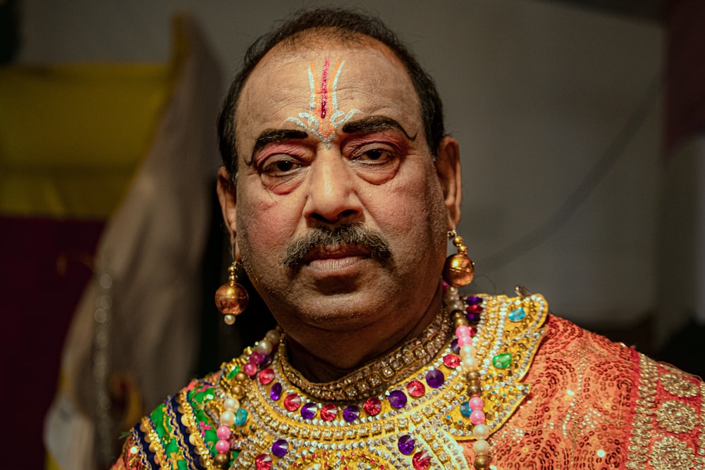 a man in a colorful outfit with a moustache on his face