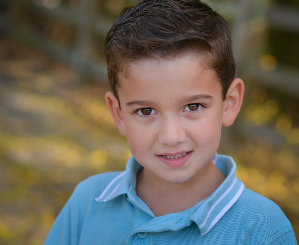 a young boy in a blue shirt posing for a picture