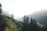 A serene mountain landscape with soft morning light and mist.