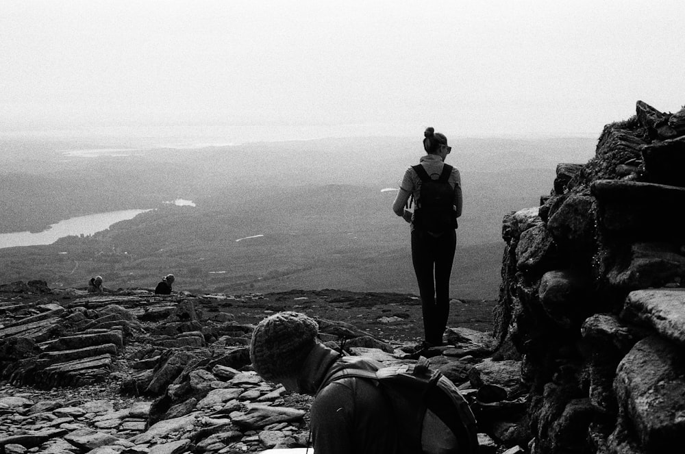 a woman standing on top of a mountain next to a man