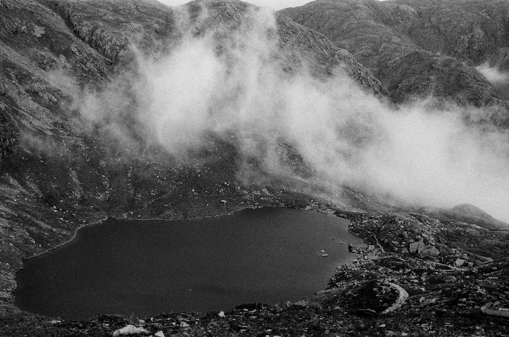 a black and white photo of a lake surrounded by mountains