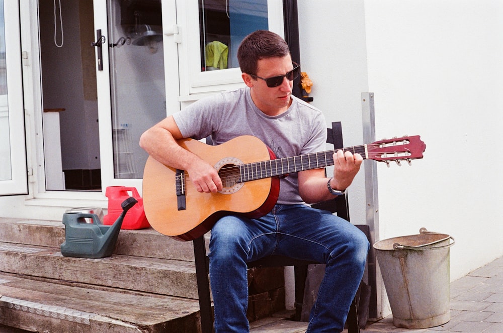 a man sitting on a bench playing a guitar