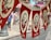 Red and white banners hanging in a row, featuring a portrait of a man with two crossed flags adorned with crescent symbols, likely representing Turkey's national flag. The word 'ATA' appears at the bottom of each banner. A blurred street scene is visible in the background, with hints of pedestrians and buildings.
