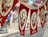 Red and white banners hanging in a row, featuring a portrait of a man with two crossed flags adorned with crescent symbols, likely representing Turkey's national flag. The word 'ATA' appears at the bottom of each banner. A blurred street scene is visible in the background, with hints of pedestrians and buildings.