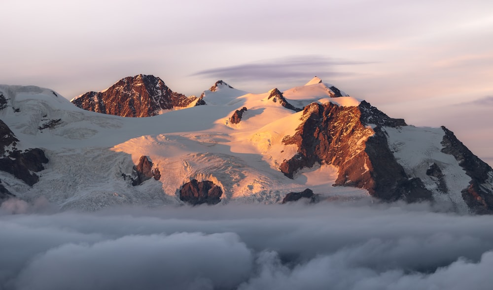 a mountain covered in snow and clouds under a cloudy sky