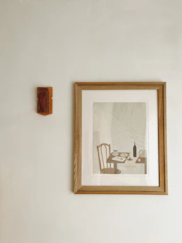 An elegant framed landscape painting hanging on a minimalist white wall.