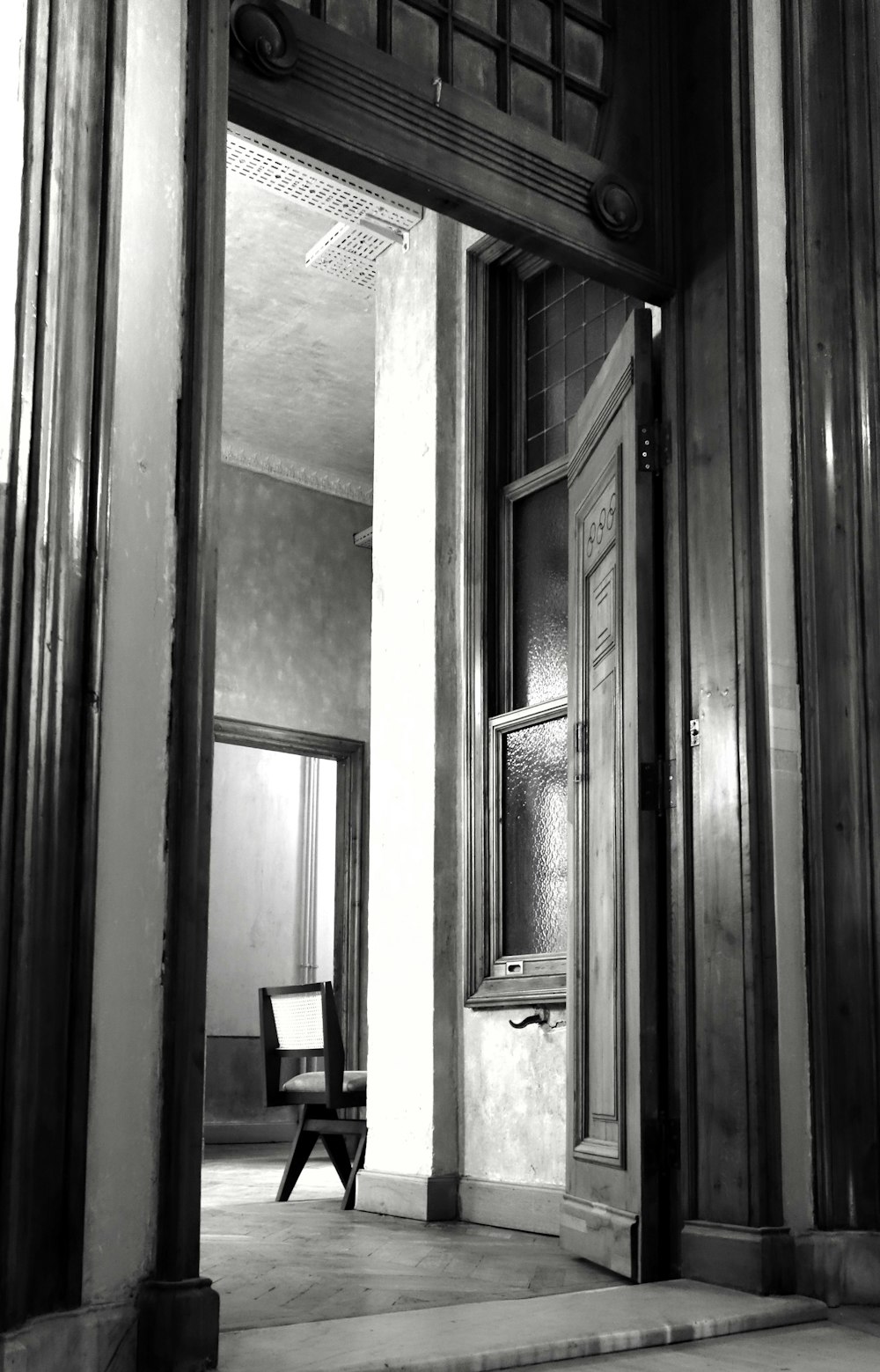 a black and white photo of a chair in a doorway