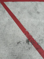 A bright red sports team logo expertly painted on a front curb with crisp lines.