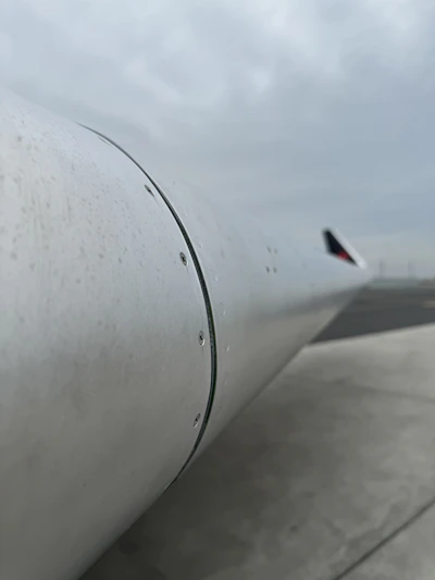 A high-resolution photo of a Boeing aircraft wing with detailed fasteners and rivets in a bright hangar.