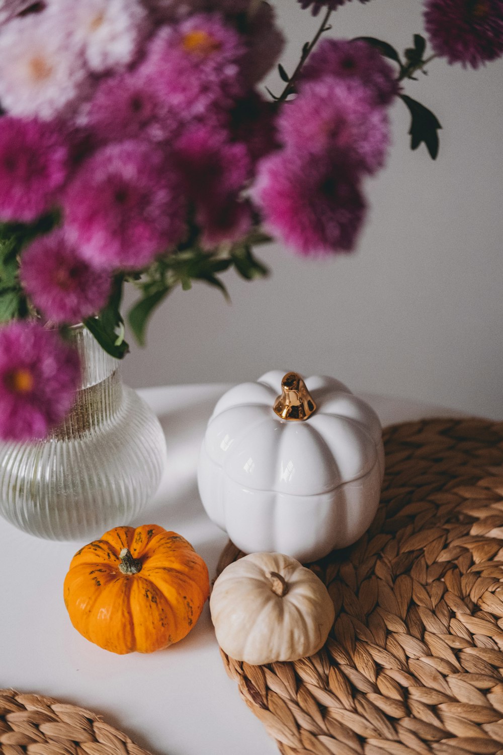 a vase of flowers and two small pumpkins on a table