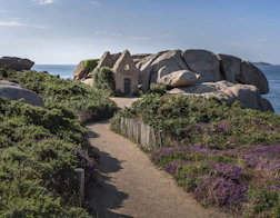 a path leading to a small house on a rock outcropping