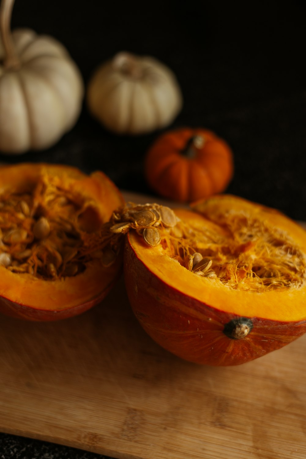 a couple of pumpkins sitting on top of a wooden cutting board