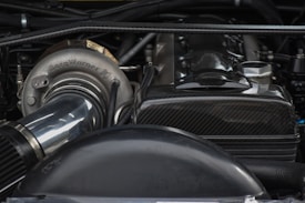 A close-up view of a car engine showcasing a turbocharger with 'BorgWarner' branding. The engine components display a mix of metallic and carbon fiber textures.