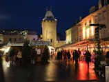 Evening scene of shoppers exploring illuminated shops with festive decorations.