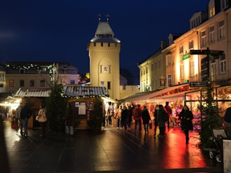 A vibrant night scene of Valdemorillo's Christmas market with colorful lights and joyful visitors.