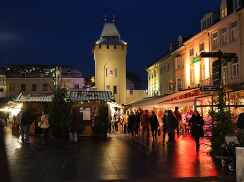 A vibrant night scene of Valdemorillo's Christmas market with colorful lights and joyful visitors.