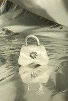 Elegant modern handbag resting on a clean white surface with sharp shadows.