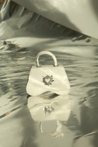 Elegant white beaded handbag with soft gold detailing resting on a white surface