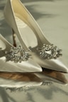 A pair of elegant, high-end shoes with sparkling embellishments displayed on a marble surface.